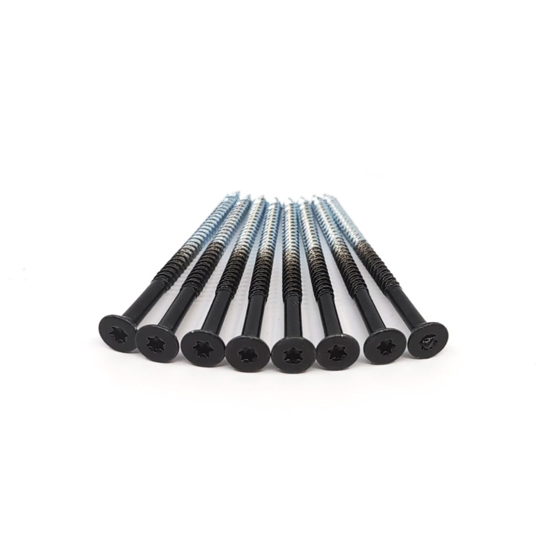 Close-up of eight #14x4 Black Flat Head Screws with ACQ Compatible Coating, featuring star-shaped drive slots, neatly aligned and angled from left rear to right front on a plain white background.