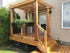 A small wooden porch with a pergola attached to a beige house has planters hanging from it. Supported by the 4x4 Triple Bundle - White/Black, steps lead up to the porch. This peaceful area includes a glass door and garden space, complemented by strong Metal Post Skirts.