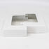 A white flat rectangular box with a clear window displays the 4x4 Double Bundle - White/Black zinc-coated metal post skirts. The open box on a plain white background highlights the sleek, durable design of these essential outdoor fixtures.