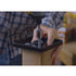 Wearing a plaid shirt, a person expertly assembles a metal bracket on a wooden post using 3/8x5 Galv. Hex Head Lag Screws (4 pcs). The workspace, like a well-equipped workshop, displays various tools with Titan Wood Post Anchors visible in the background.