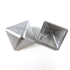 Two Quick Cap Aluminum pyramid-shaped objects are shown. One stands upright with its square base inscribed with text, while the other lies on its side, displaying its smooth shape. The reflective metallic surfaces highlight their decorative potential as post caps.