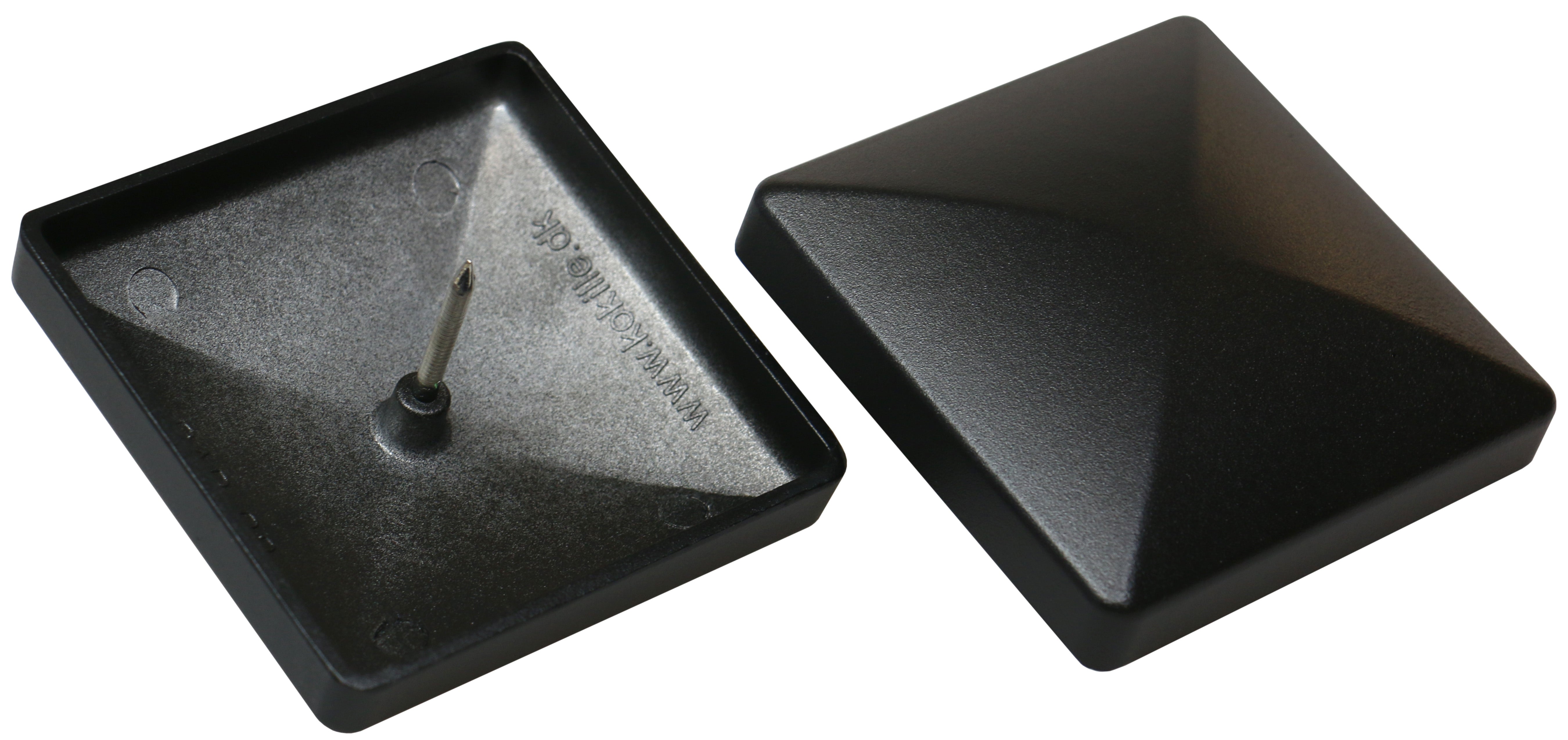 Two black plastic shoplifting tags are displayed. One is open with a central pin, echoing the precision of Quick Cap Aluminum, while the other is closed with a smooth pyramid surface. Both have triangular designs reminiscent of sleek cast aluminum post caps.