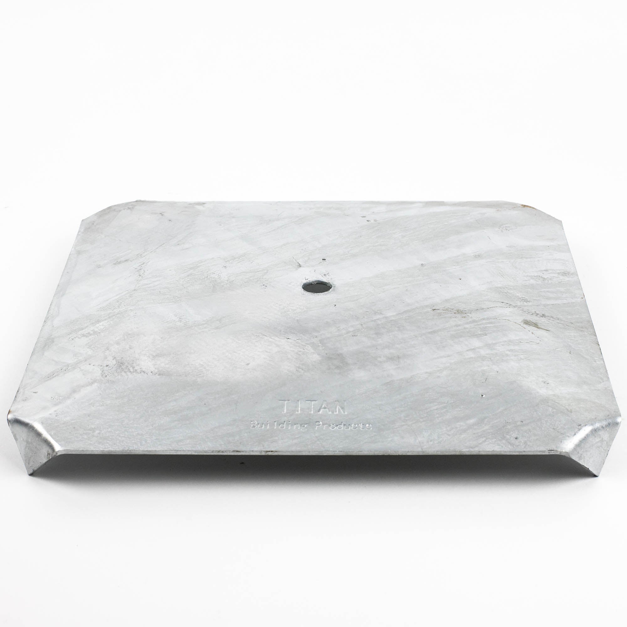 A brushed rectangular metal plate with rounded corners and a central hole, ideal for ground footings. Subtle diagonal patterns adorn the surface, featuring text that partially reads Titan and Products. Product Name: Deck Foot - Floating - Ground Contact.
