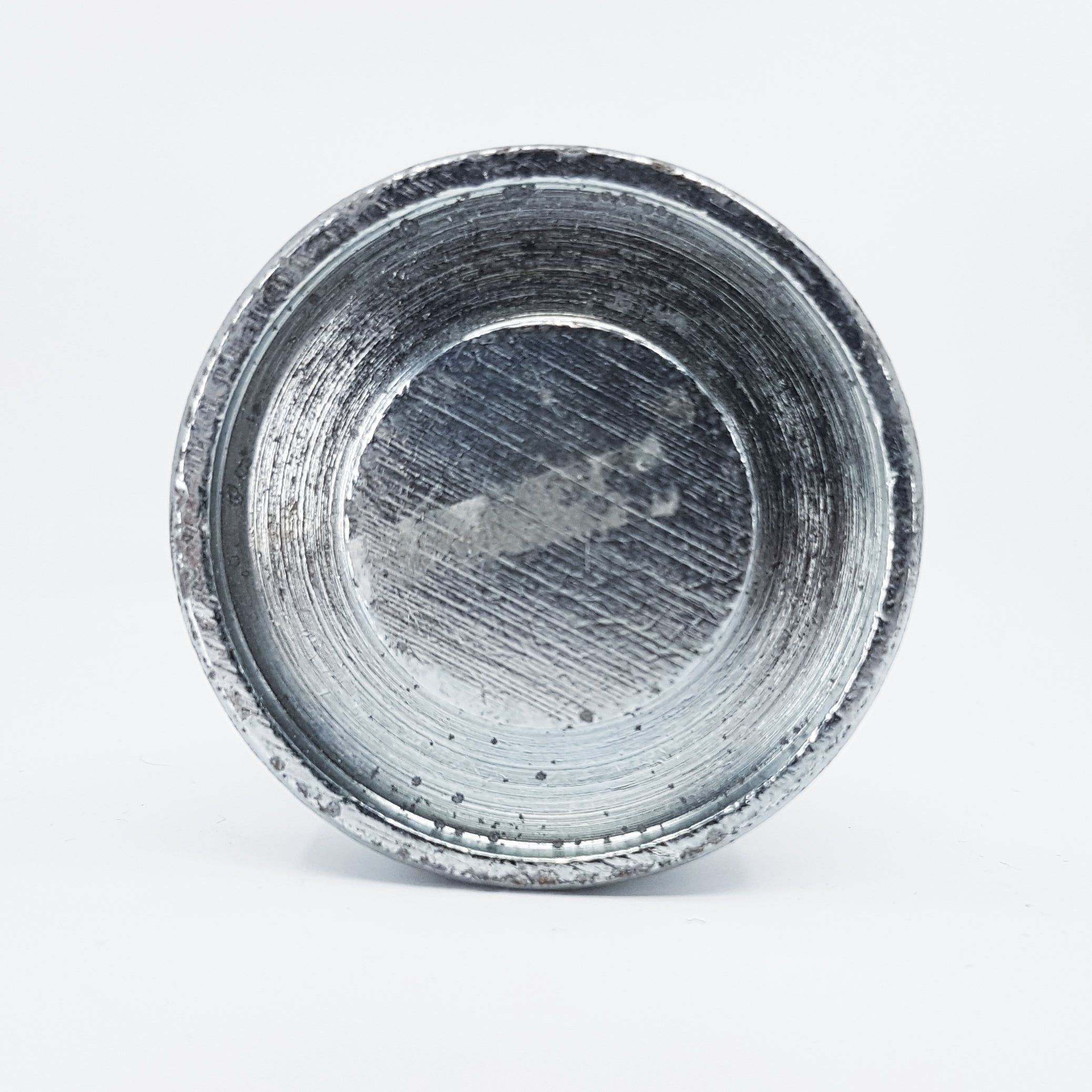 A rusted, empty steel bowl sits on a flat, white surface like a used Hammer Tool - 44. Its inner surface is scratched and worn, adding texture to the round vessel against the plain white background.