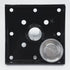 The Hammer Tool - 44 is a black square metal plate with eight small holes and a central hole ideal for 4x4 post anchors. A recessed-center circular silver metal piece is next to it, designed for builders, all set against a plain white background.