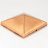 The Pyramid Metal Post Cap is a square, pyramid-shaped copper cap with a smooth, shiny finish. It features a small hole on one side and stands out beautifully against a plain white background.