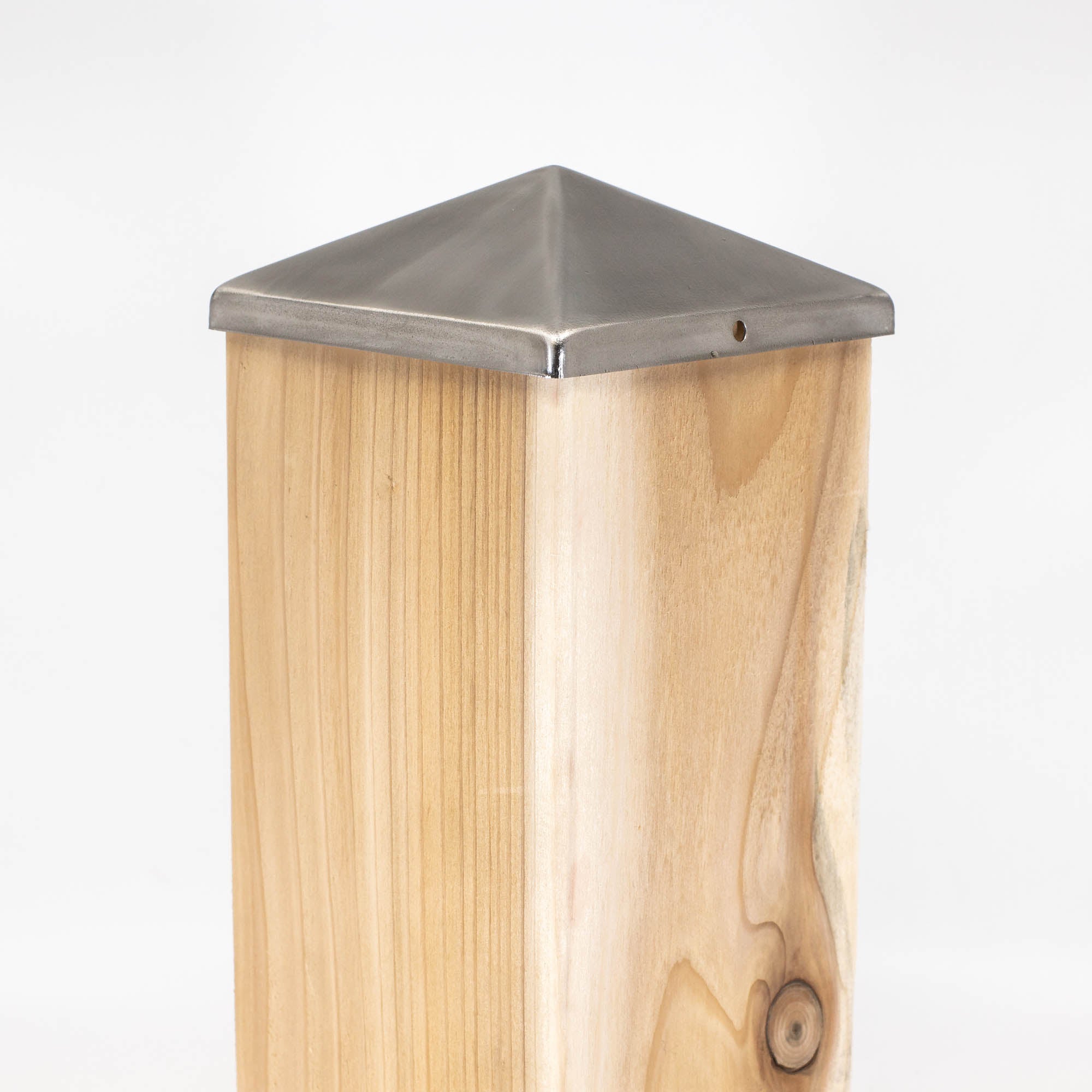 This wooden post features a Titan Wood Post Anchor and is elegantly crowned with a Pyramid Metal Post Cap. The visible wood grain contrasts beautifully with the gleaming metal cap against a simple white background.