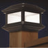 The Classy Post Cap Colonial Solar lamp is a decorative outdoor piece with square pebbled glass panels, a dark cast aluminum frame, and sits elegantly atop a wooden deck railing, glowing softly at dusk.
