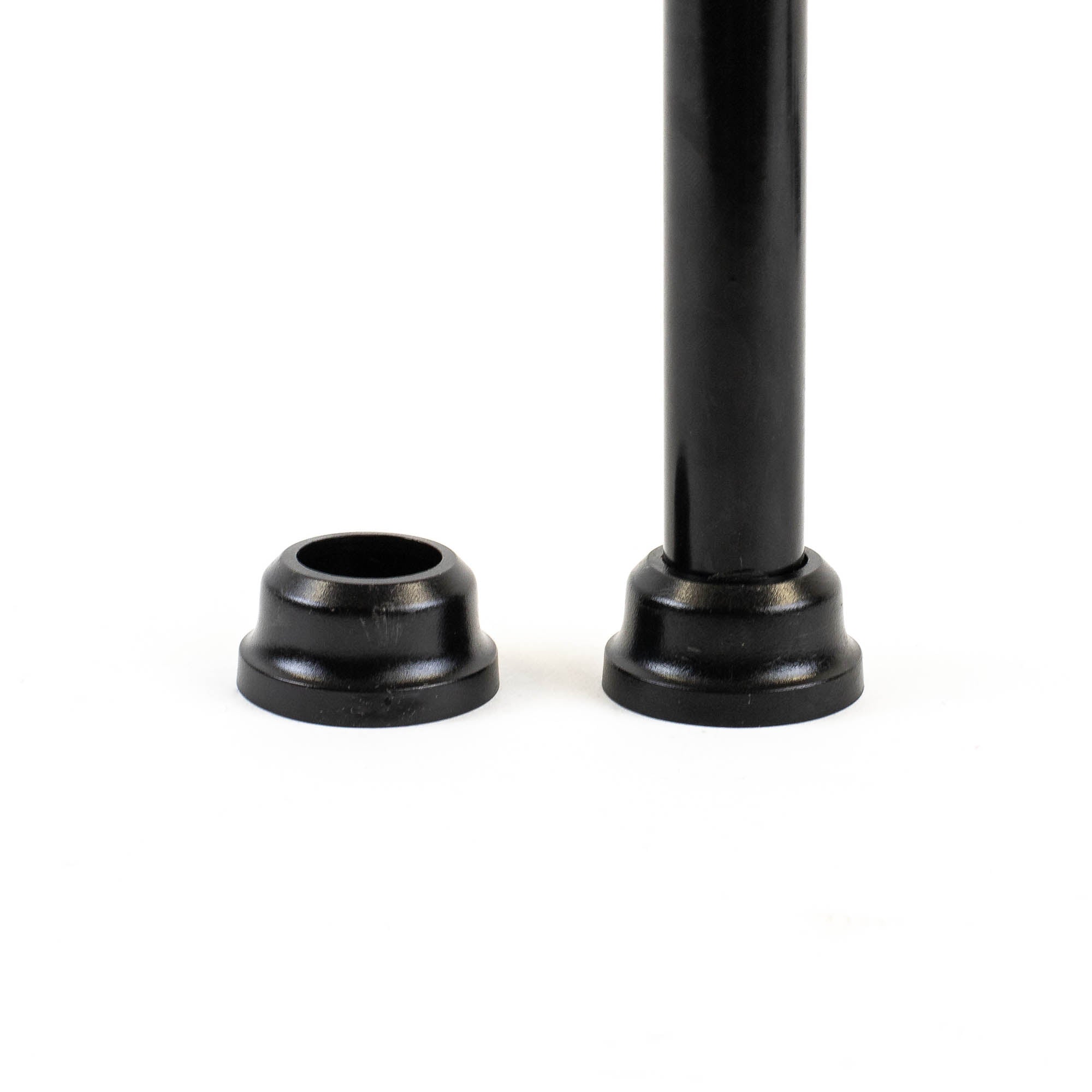 A black metal rod, resembling aluminum balusters, stands vertically on a flat surface beside a detached glossy black cap. The setup evokes the sleek design of Snapn Lock® Fence Toppers™ - Round with the cap positioned separately to the left of the rod.