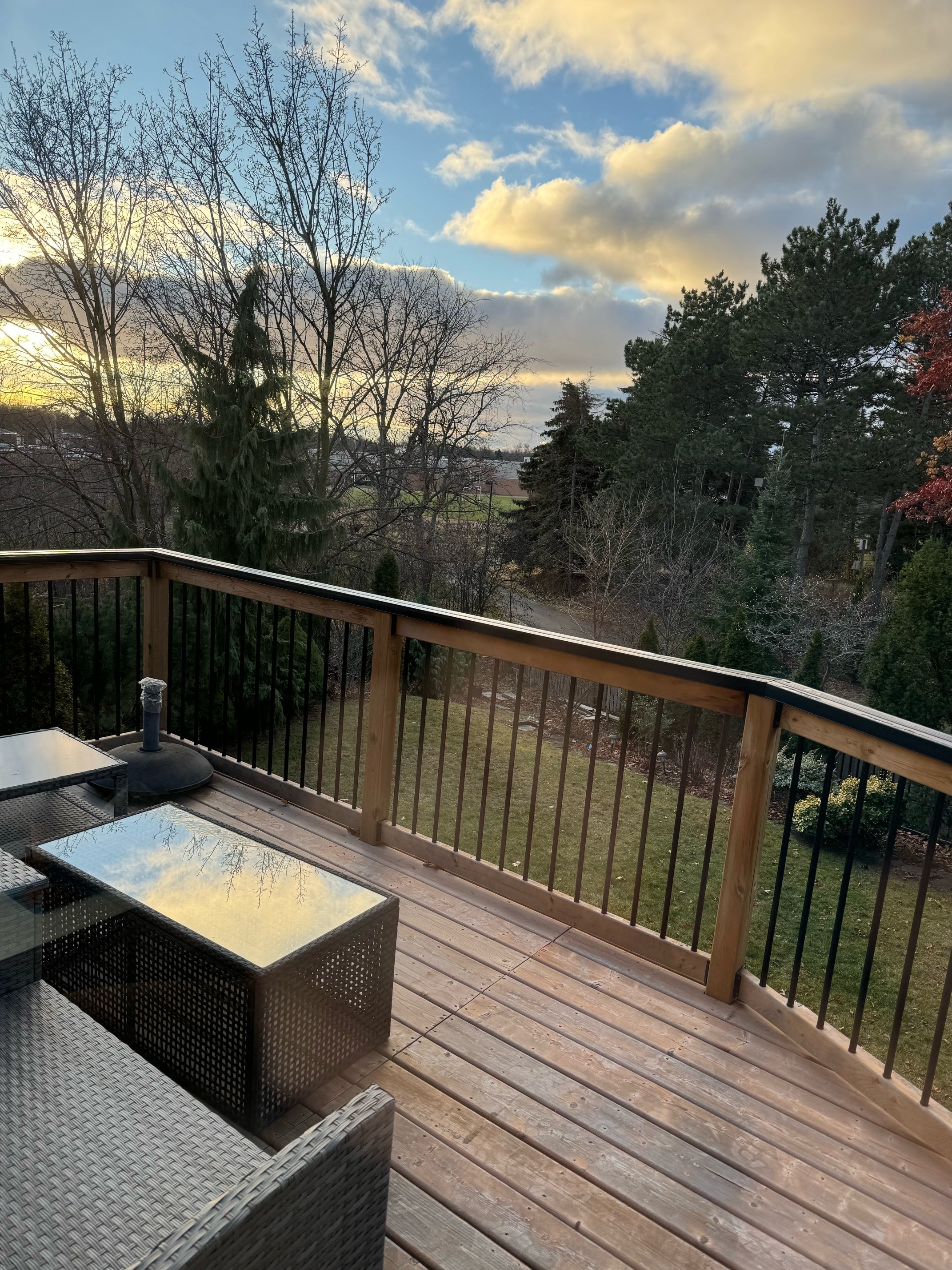 Outdoor deck with railing and air conditioning unit against a blue sky with clouds