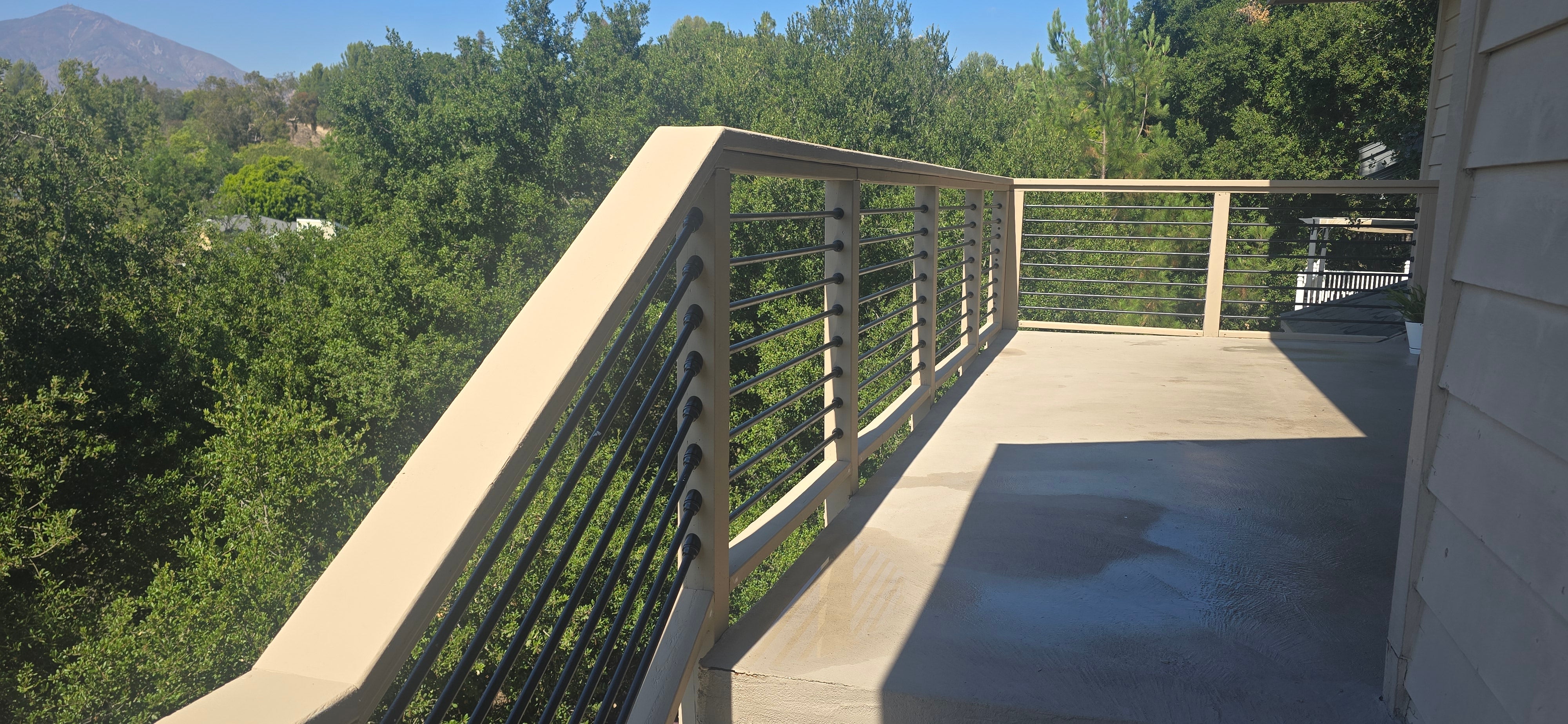 Wooden deck with railing overlooking green trees on a sunny day
