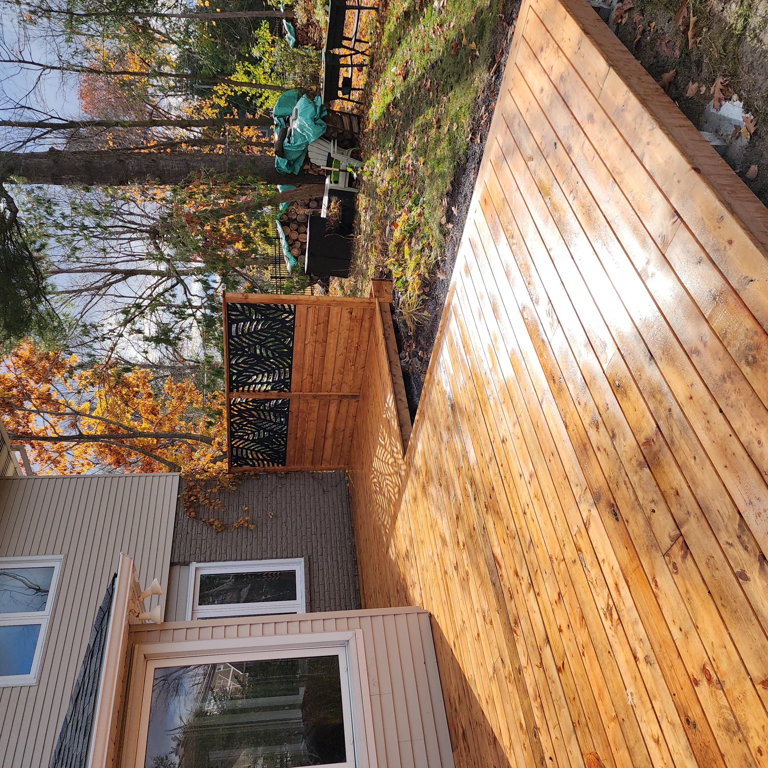 Wooden deck extending from a house with trees and a grill in the background