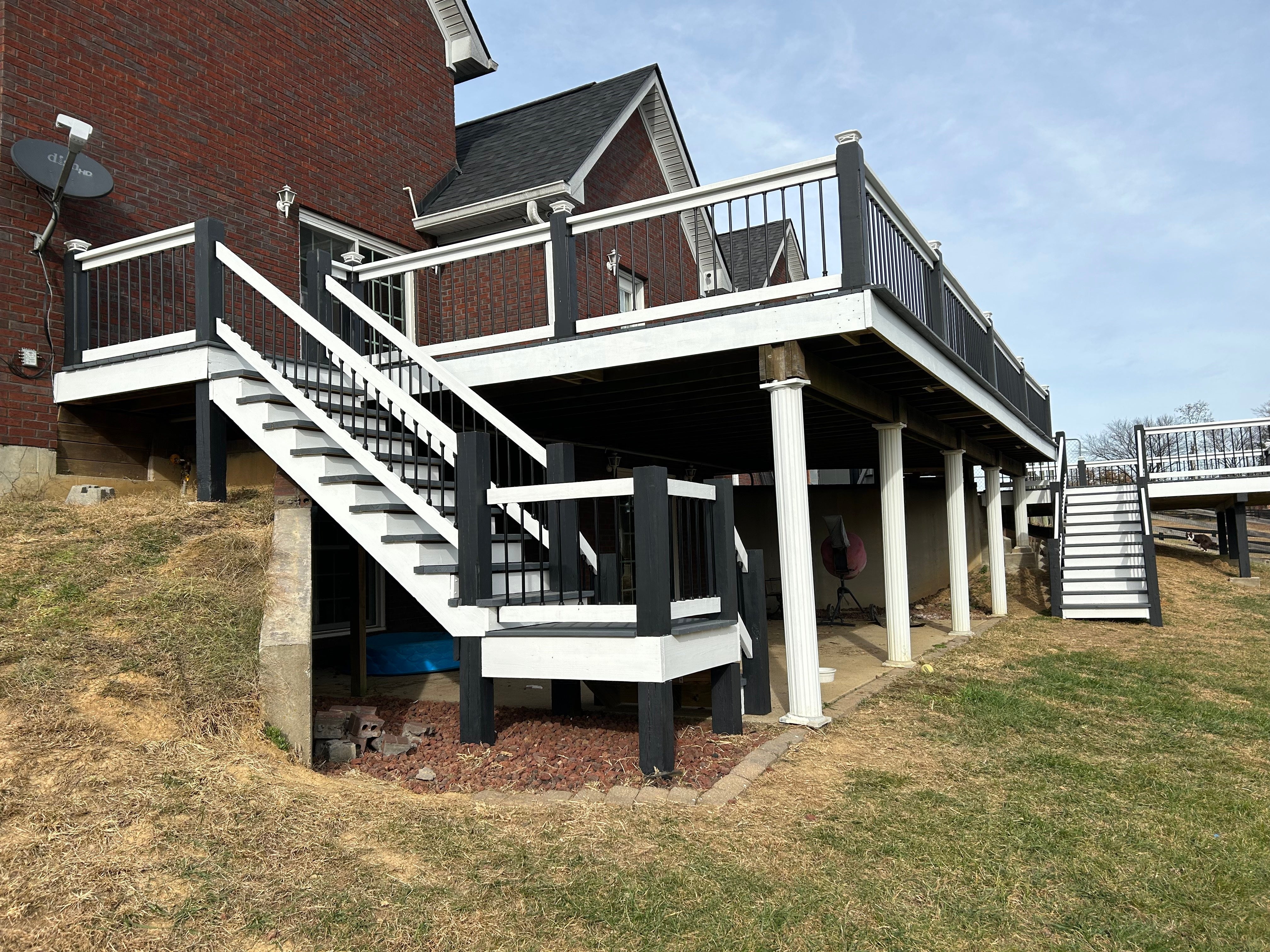 Two-story deck with white railings and stairs leading to a house.
