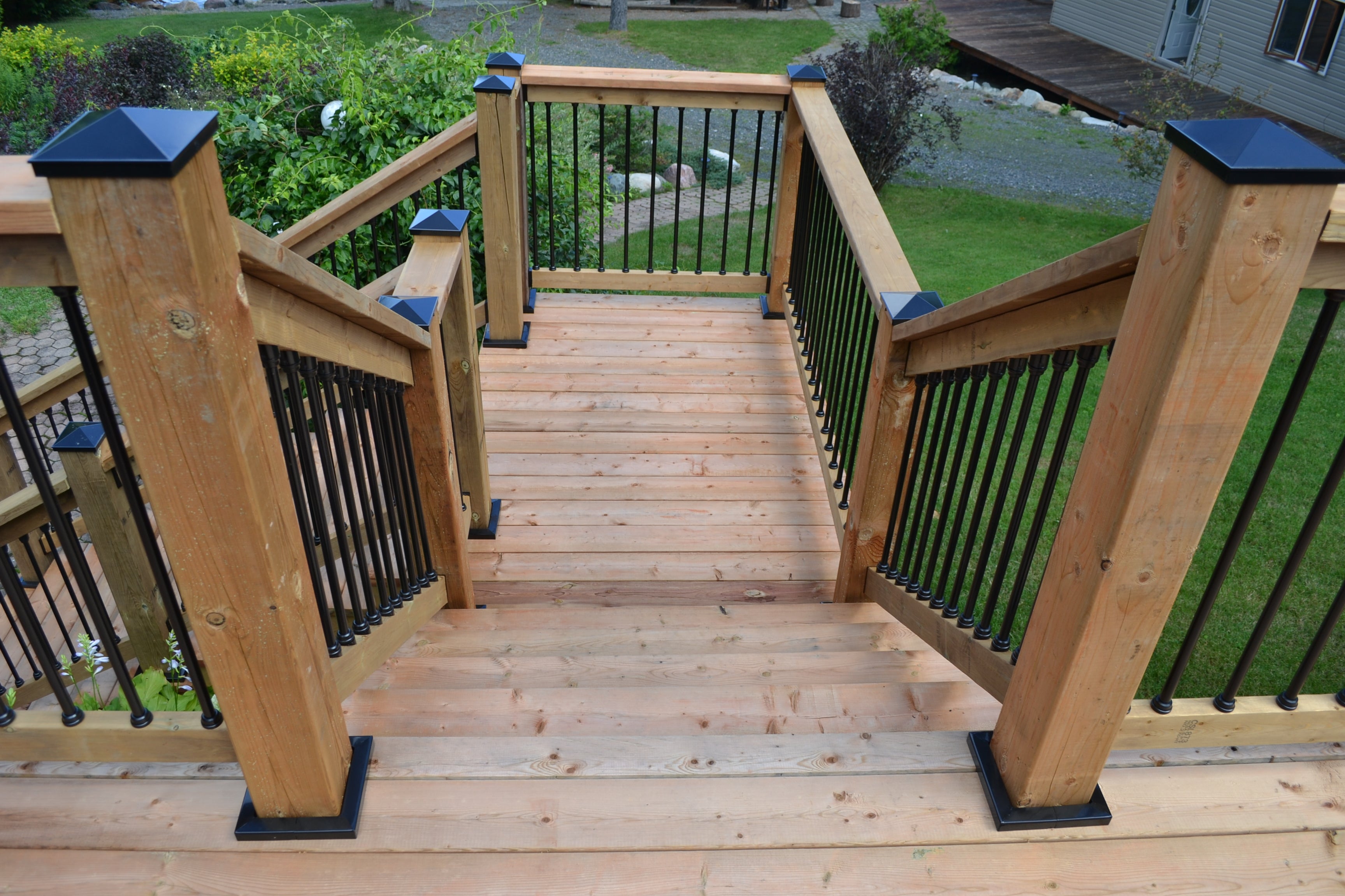 Wooden staircase with black railings leading to a deck.