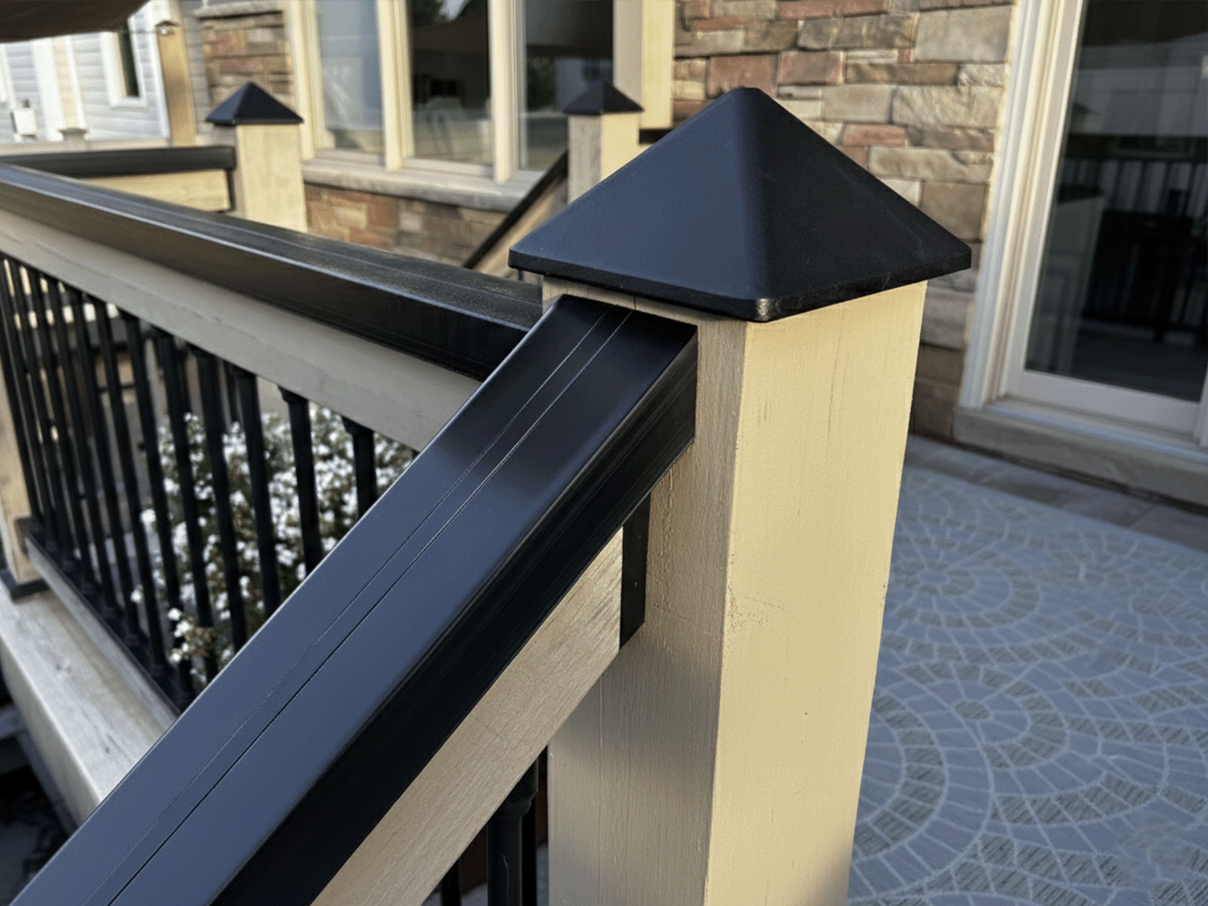 Railing system with black metal balusters and wooden posts on a patio.