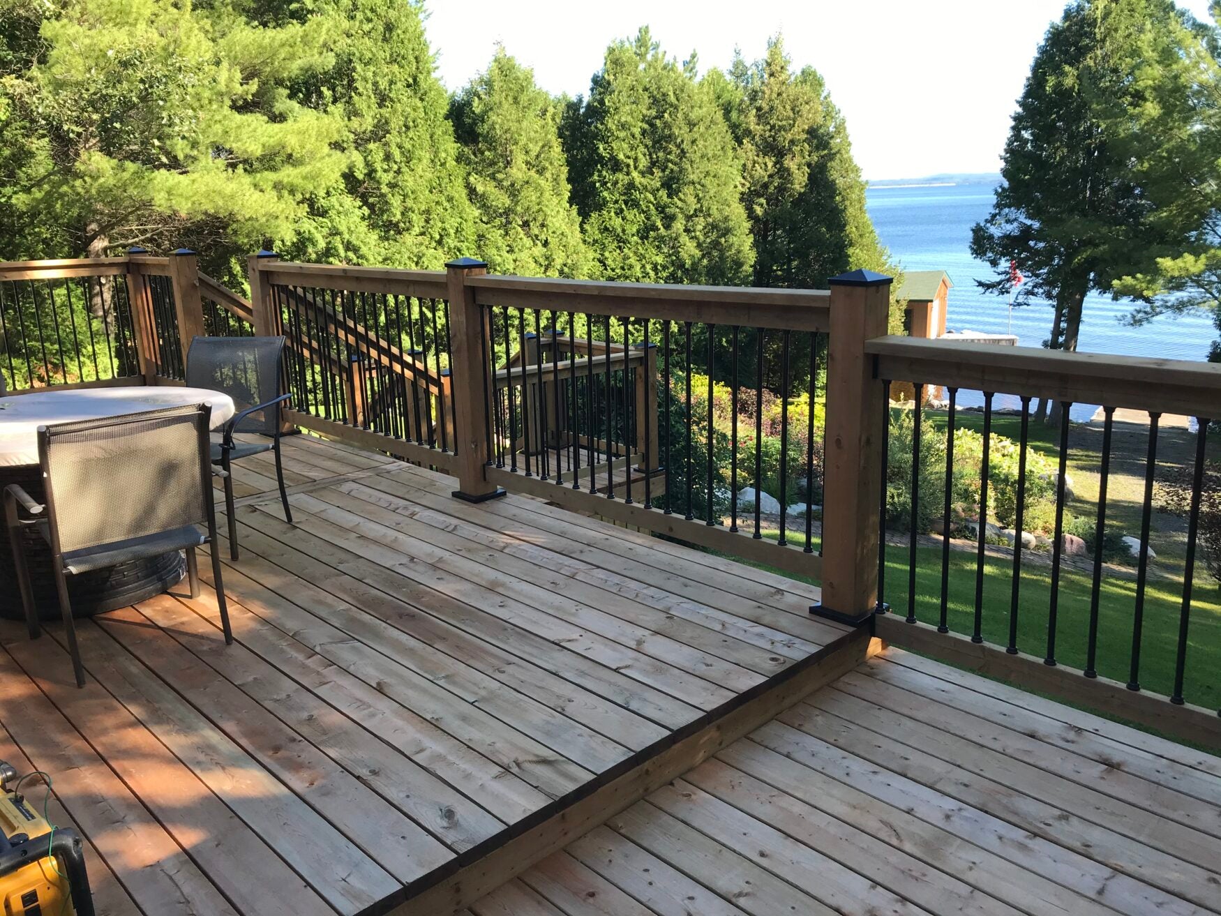 Wooden deck with railing overlooking a scenic view of trees and water.
