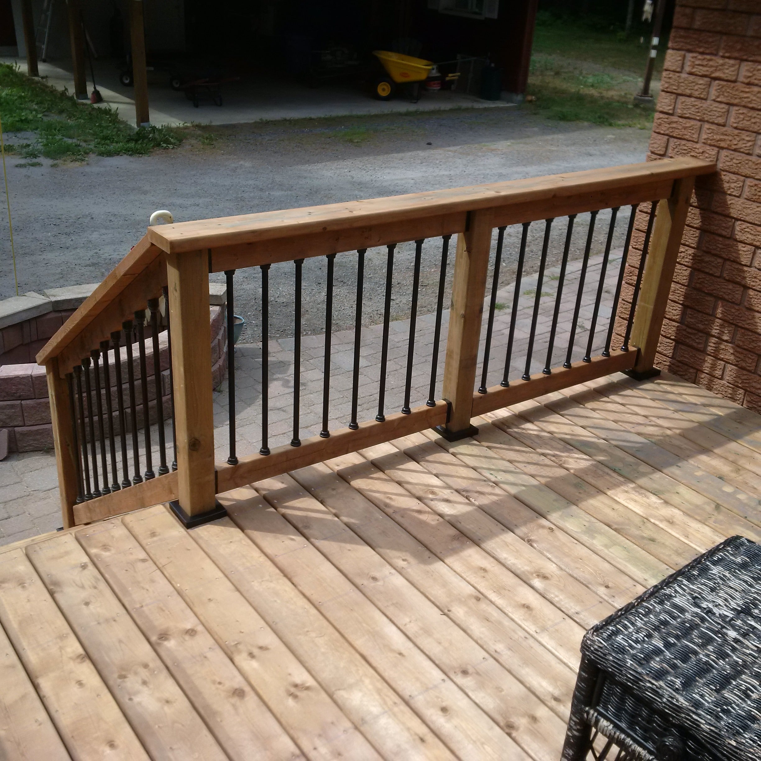 wood railing overlooking a paver patio  and a well