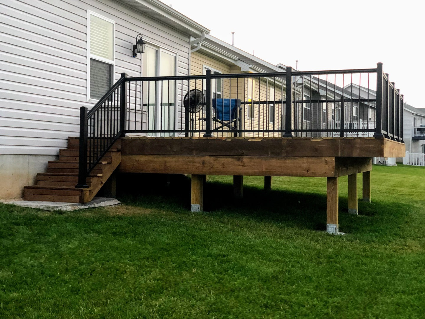 Wooden deck with black railing in front of a house