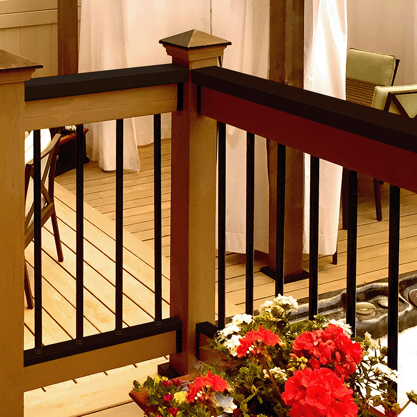 Decorative railing with black metal bars on a wooden deck, featuring potted flowers.
