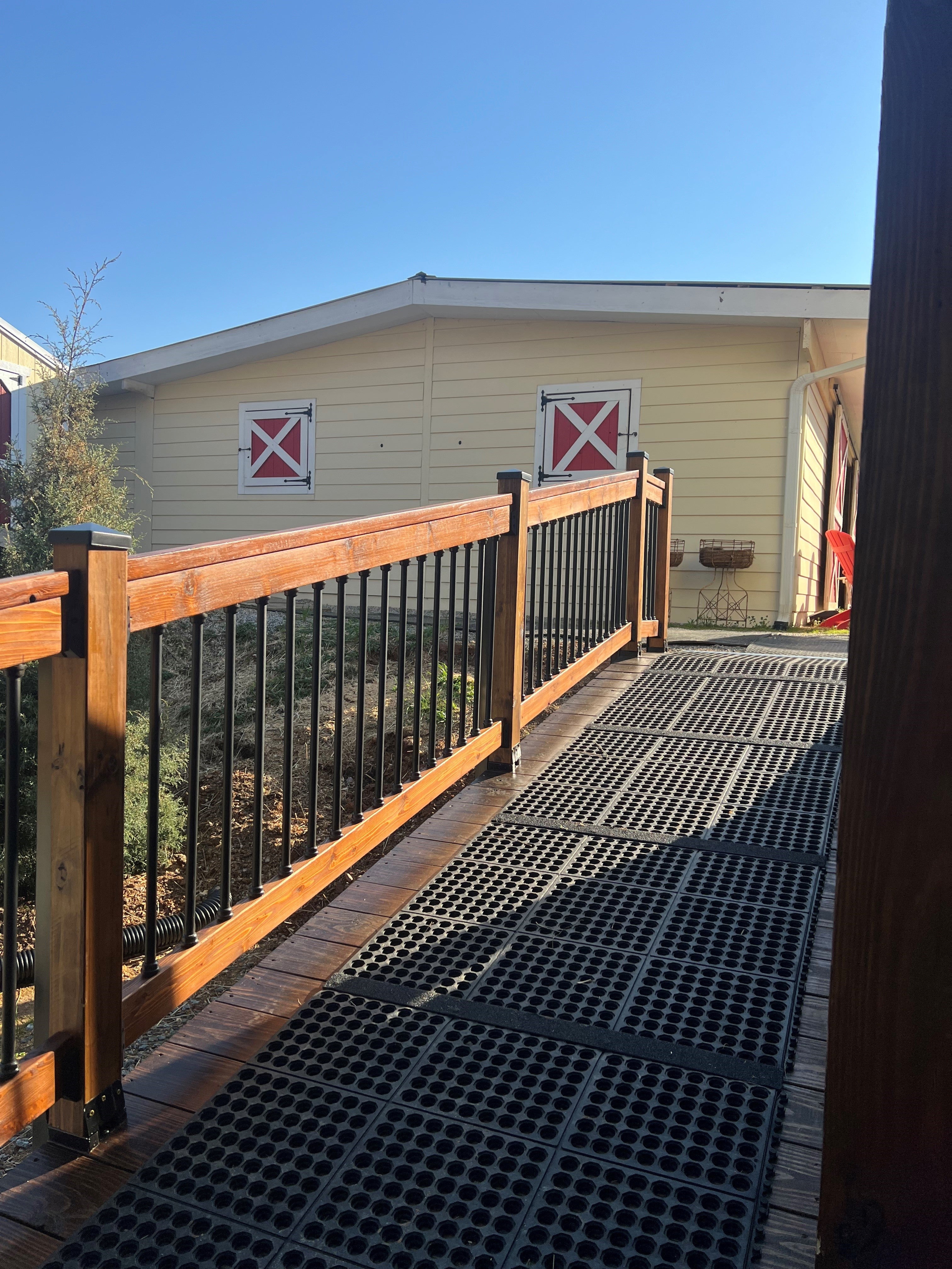 Wooden deck with metal railing leading to a yellow building with red and white signs.