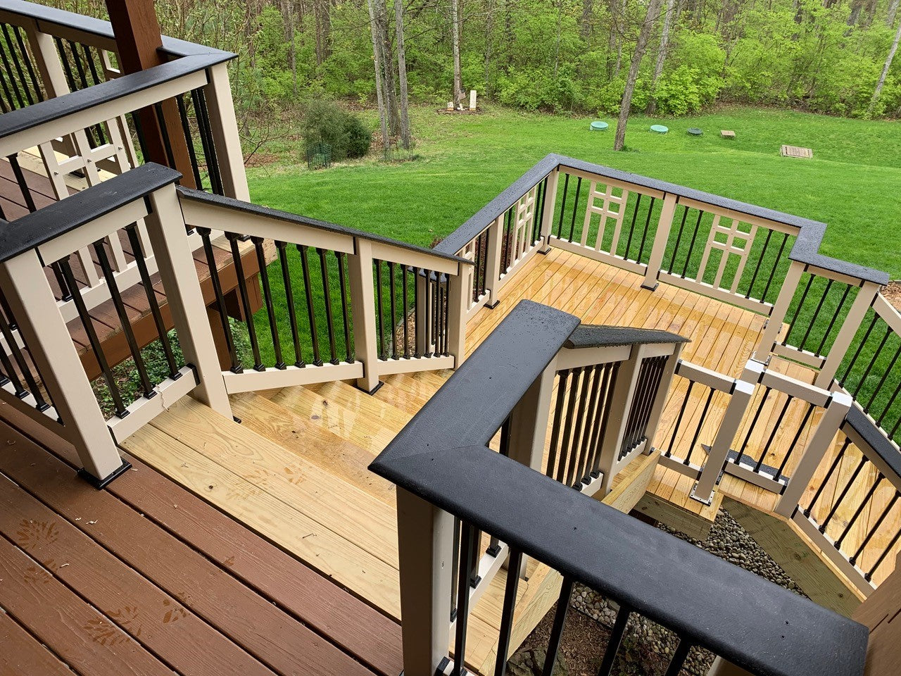Wooden deck with railings and a view of a grassy yard and trees.