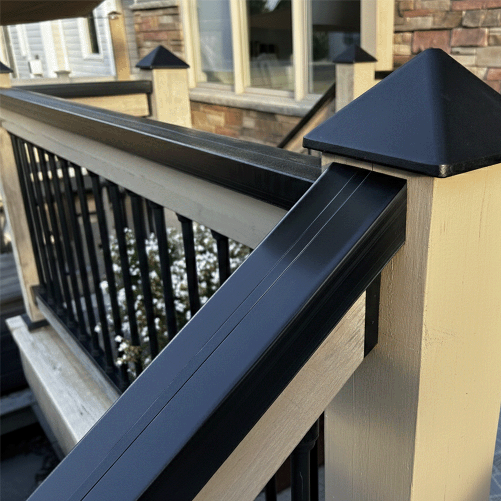 Railing with black pyramid-shaped post cap as well as black balusters on a wooden deck
