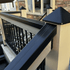 Railing with black pyramid-shaped post cap as well as black balusters on a wooden deck